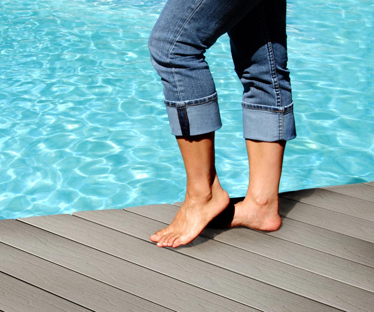 Person standing on composite decking by pool.