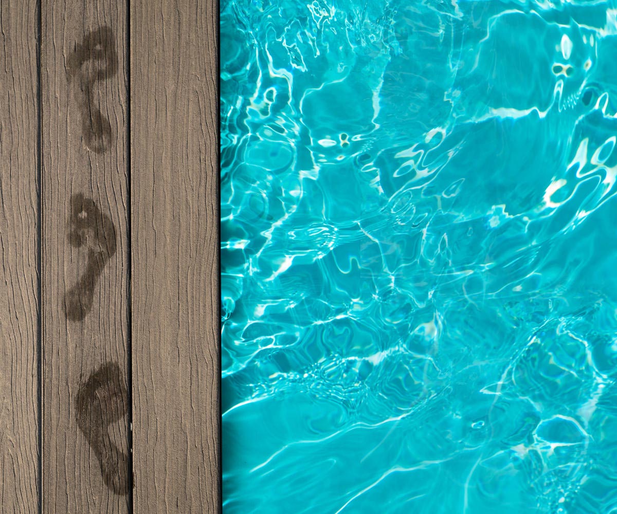 Poolside composite decking with wet footprints.