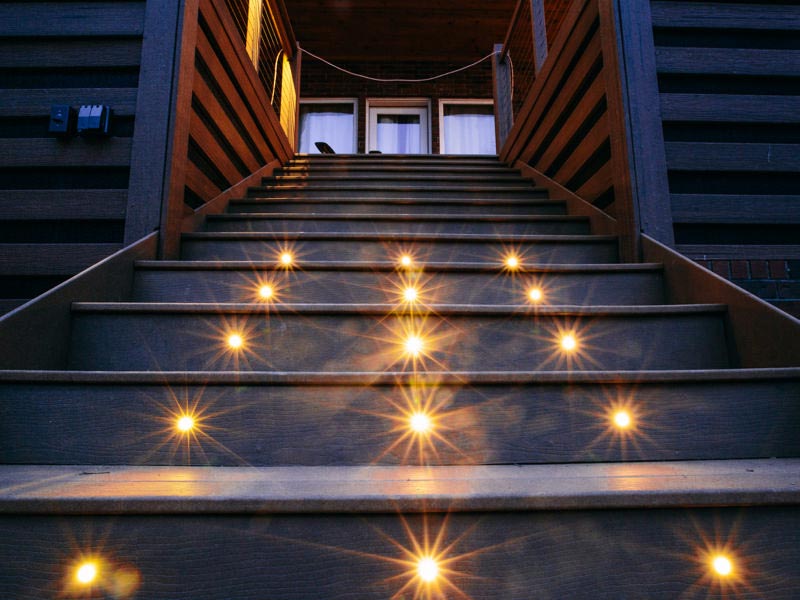 Close upward view of MoistureShield stair lighting on a set of gray stairs.