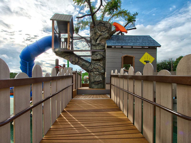 Raised MoistureShield composite decking path leading to a treehouse with a slide.