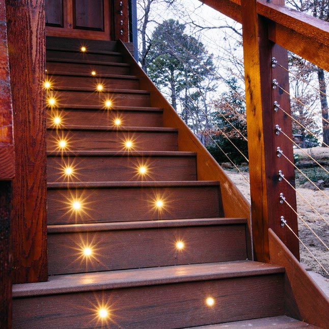 Close upward view of MoistureShield composite deck stair lighting on a set of brown stairs.