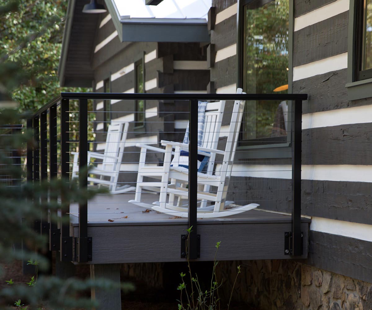 Gray elevated composite deck with black railing and white rocking chairs.