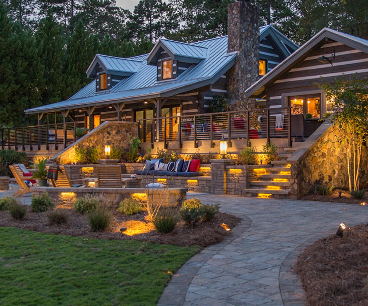 High-end cabin with well-lit composite decking wraparound porch.