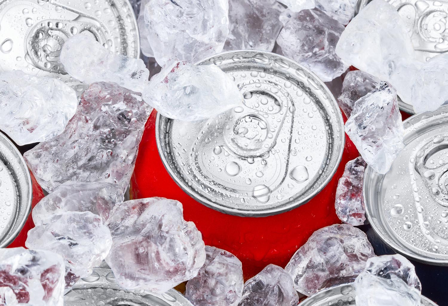 Close overhead view of soda cans and ice cubes.