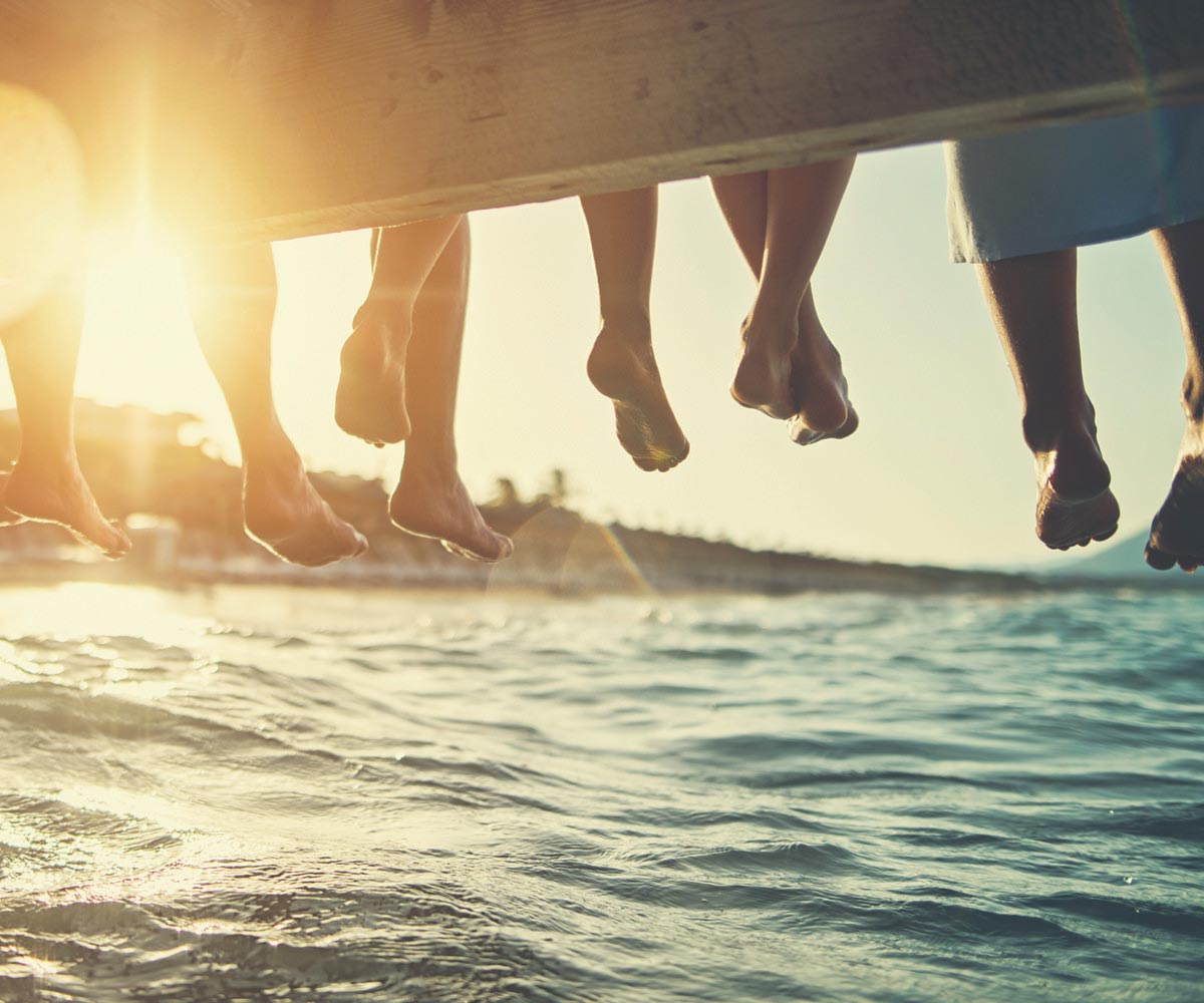 View from underneath a dock with feet hanging over water.