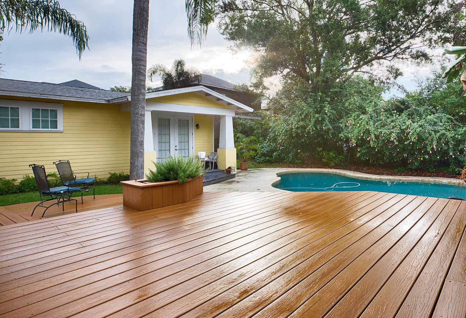 worry-free Yellow house with white trim and brown composite pool deck.