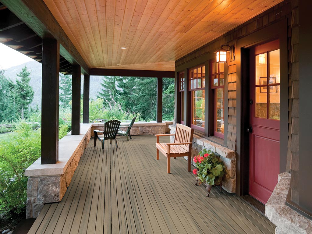 MoistureShield's Elevate composite decking covered front porch with a wooden bench and two wooden chairs.