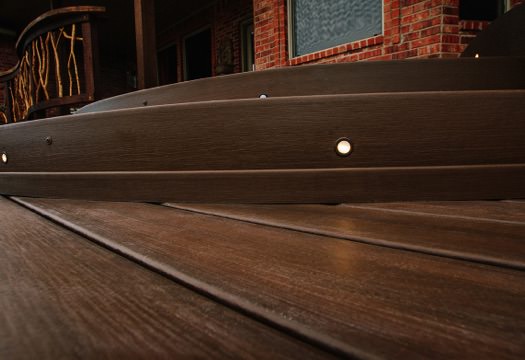 Close view of dark brown composite decking stairs with inset lighting.