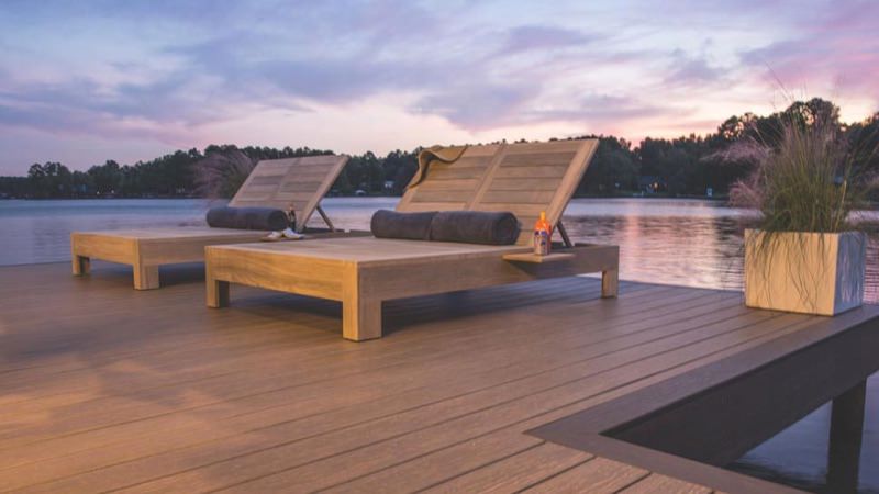 Composite deck with wood lounge chairs overlooking a lake.