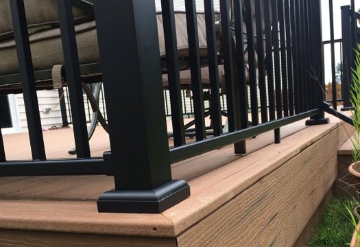 Close view of the bottom corner of black aluminum deck railing.