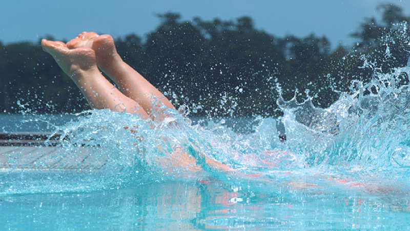 Feet and splash of a person diving into a pool.